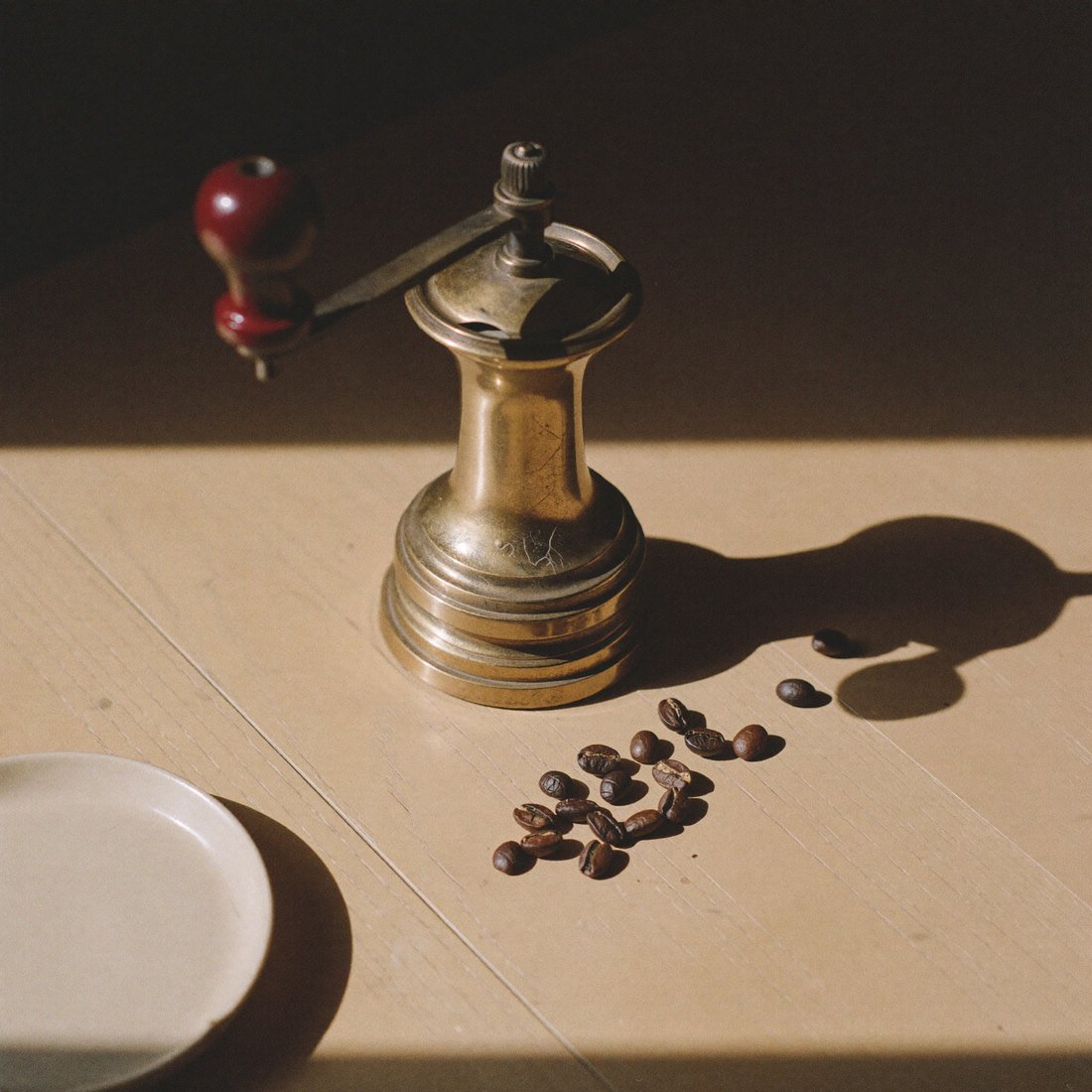 Grãos de café e moedor sobre superfície de madeira